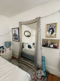 a mirror in a bedroom with a bed and a bedside table